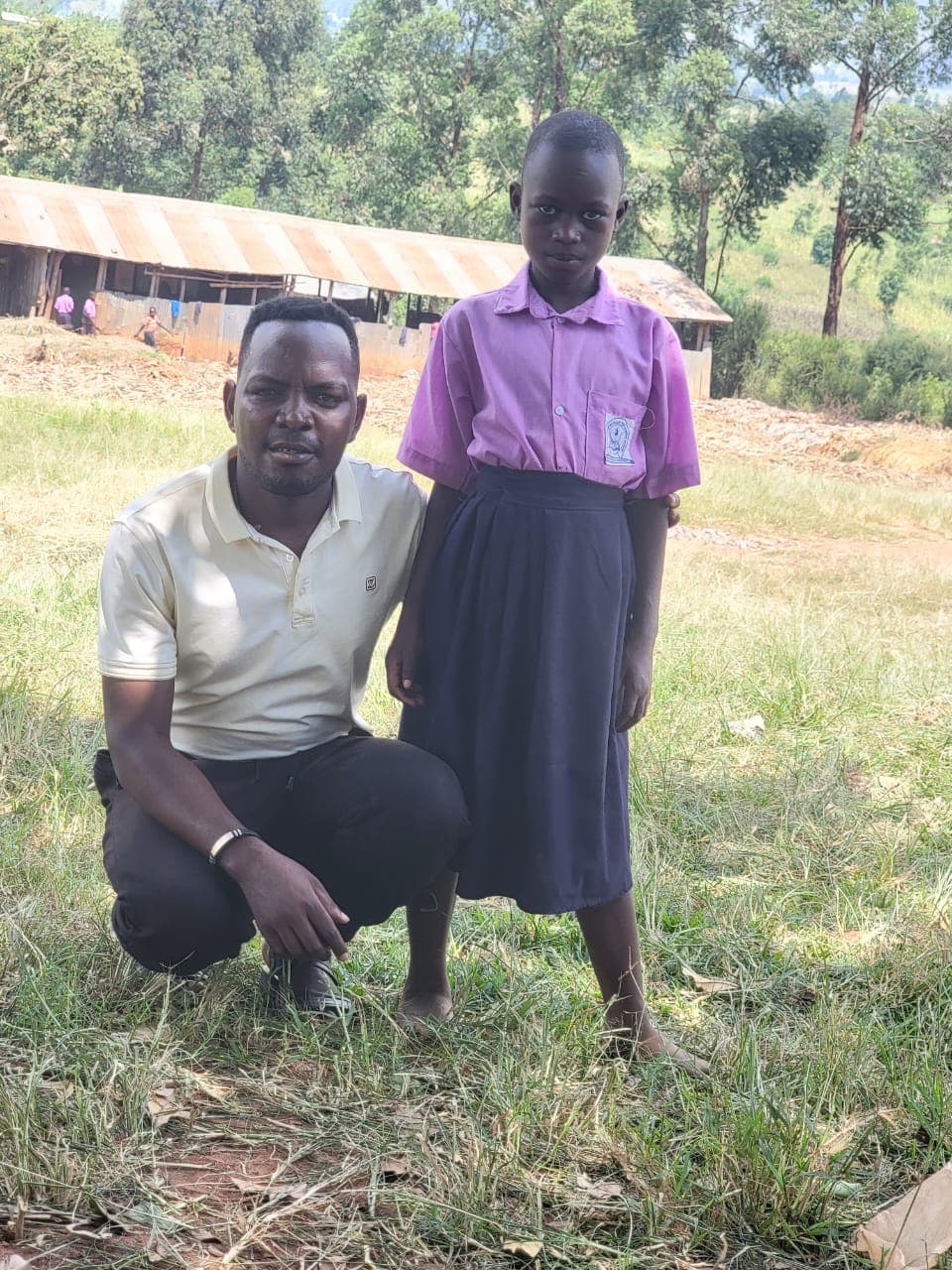 A team member with a girl in her school uniform at a school in Uganda